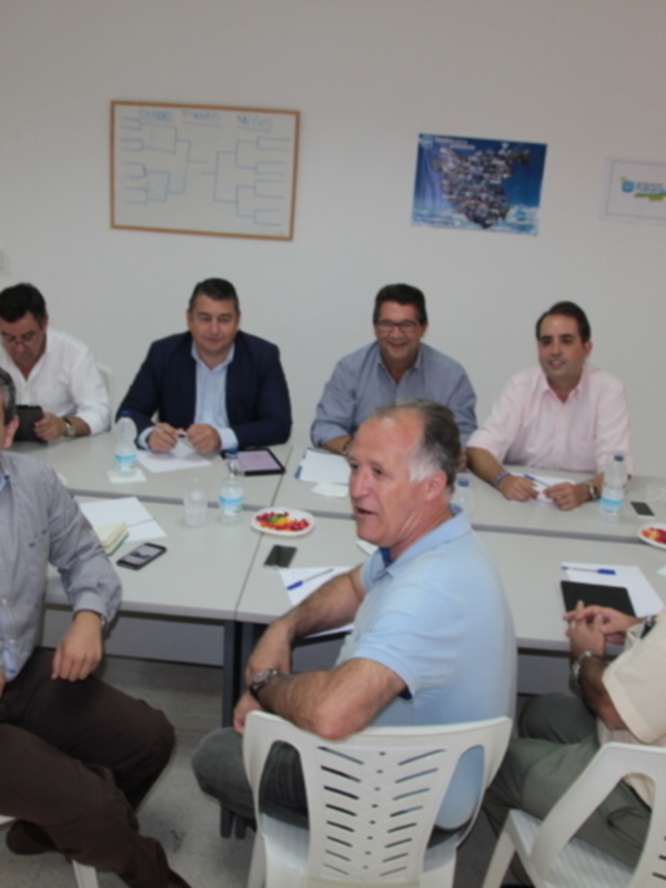 Reunión de trabajo en una sala de reuniones con varios participantes sentados alrededor de una mesa.