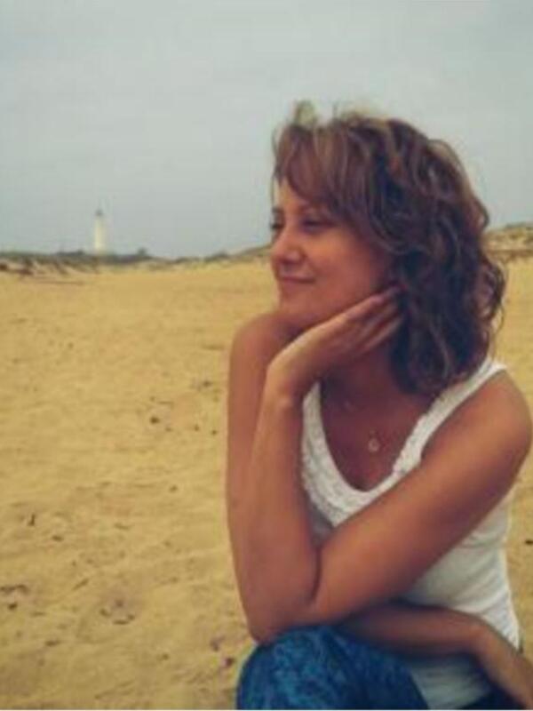 Persona relajada en la playa con un faro al fondo.