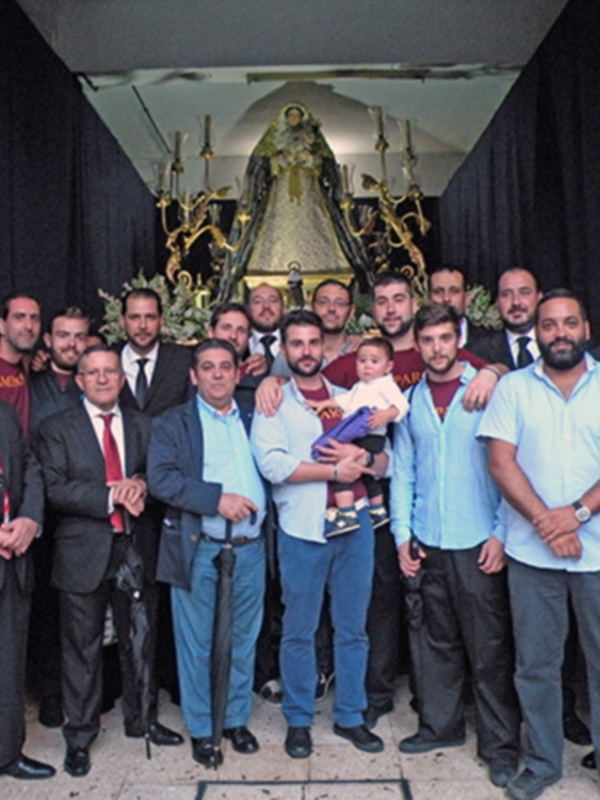 Un grupo de personas posa para una foto frente a una imagen religiosa en un entorno urbano.