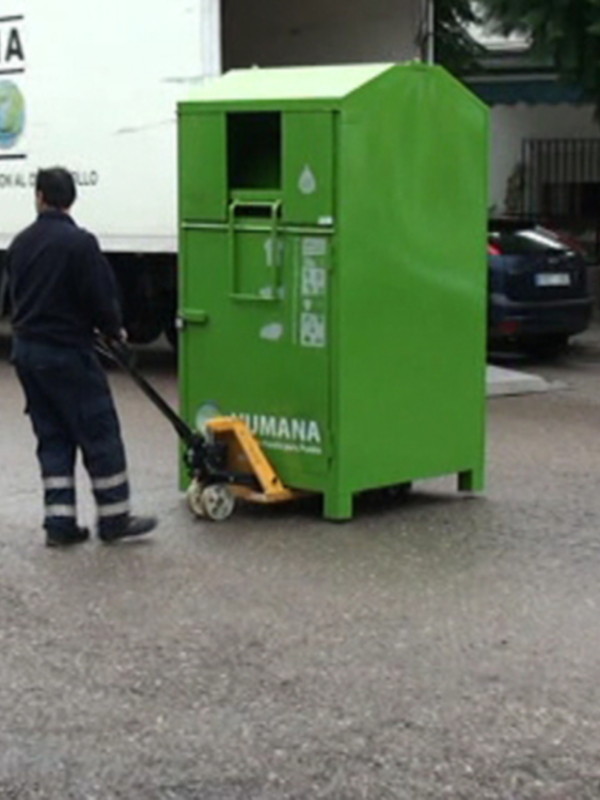 Operario recogiendo residuos de una contenedor verde de Humana en la calle.