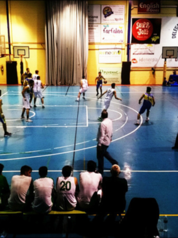 Jugadores de baloncesto en acción durante un partido en una cancha deportiva iluminada.