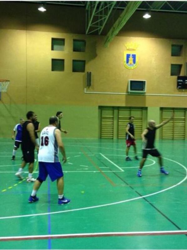 Jugadores de baloncesto en acción durante un partido en una cancha deportiva municipal.