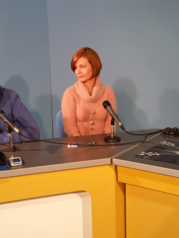 Tres personas sentadas en una mesa de radio con micrófonos, discutiendo en un estudio de transmisión.