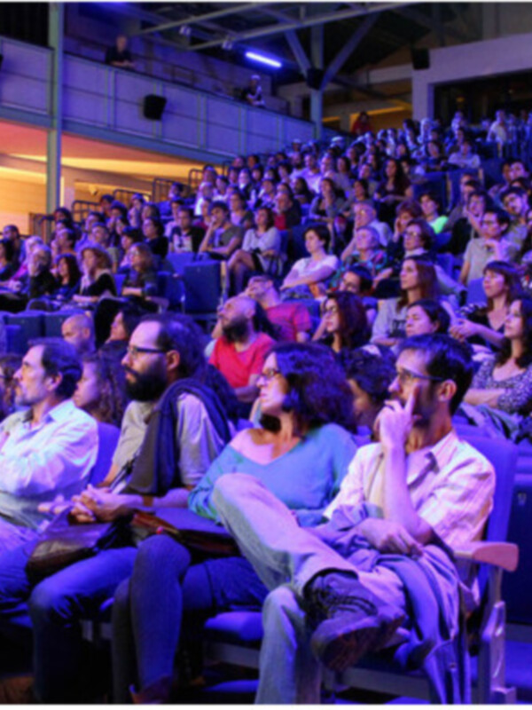 Asistentes de un evento cultural en Sevilla, España, disfrutando de la proyección de una película en el Festival de Cine Europeo.