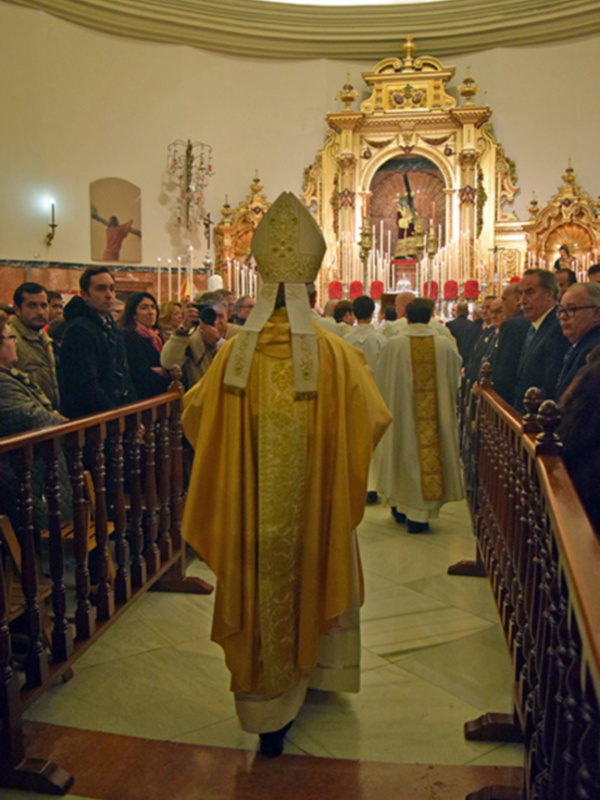 Eucaristía en una iglesia con sacerdote vestido de amarillo y fieles en el coro.