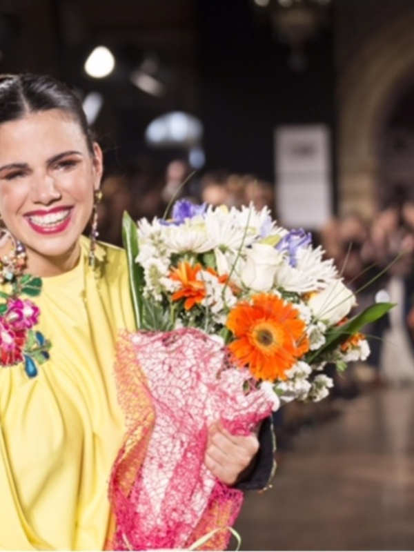 Elegante mujer con un vestido amarillo y flores en un evento formal.