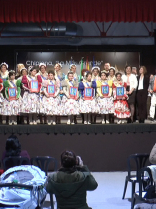 Desfile de trajes típicos en un evento cultural con público asistiendo.