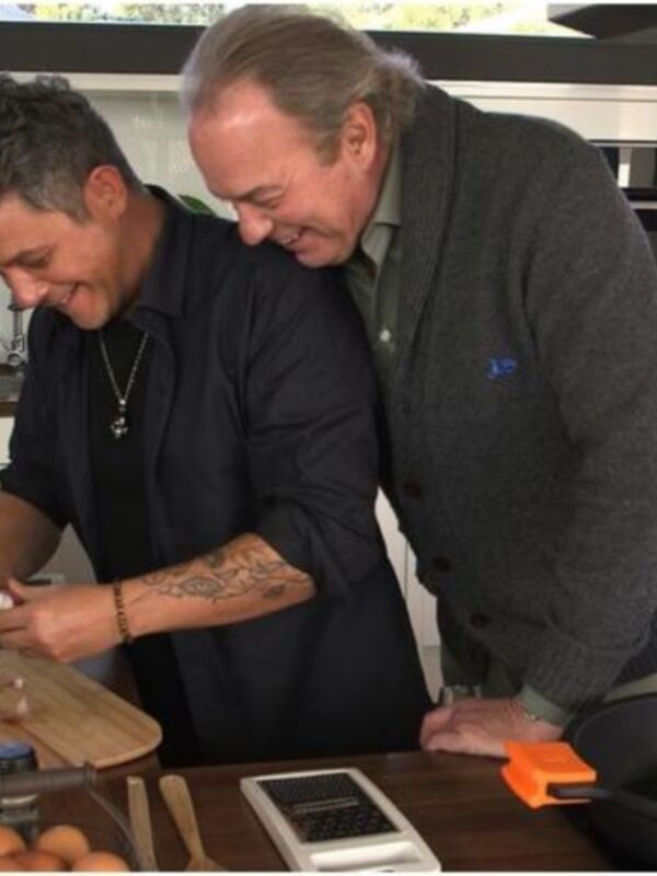Dos personas cocinando juntas en una cocina moderna, compartiendo un momento de risa y colaboración.