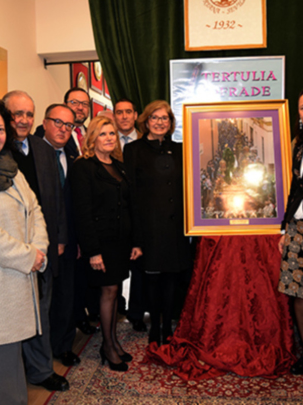 Celebración de la Tertulia de la Hermandad de la Esperanza con un grupo de personas posando junto a una obra de arte titulada 'Tertulia'.