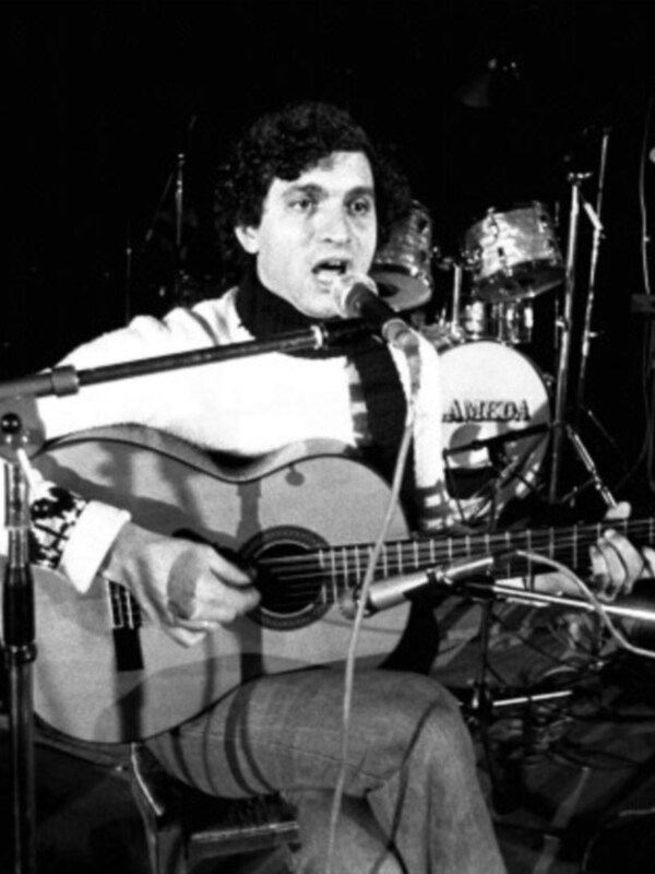 Un músico en un concierto, tocando una guitarra acústica.