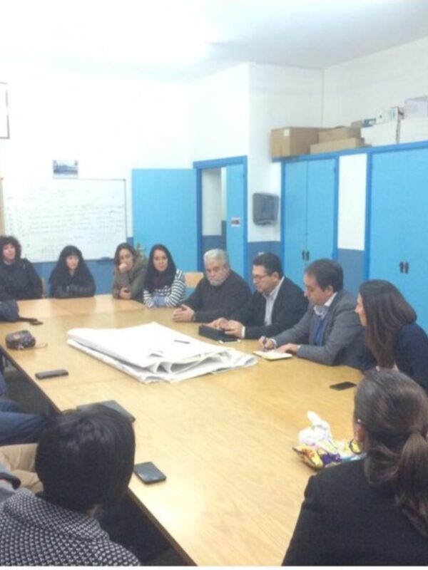 Reunión de trabajo en una sala de conferencias con participantes sentados alrededor de una mesa.