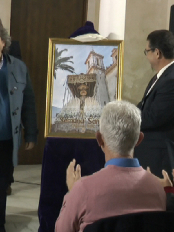 Presentación de un cuadro en una conferencia o evento público, con personas en el escenario y en el público, en un ambiente formal.