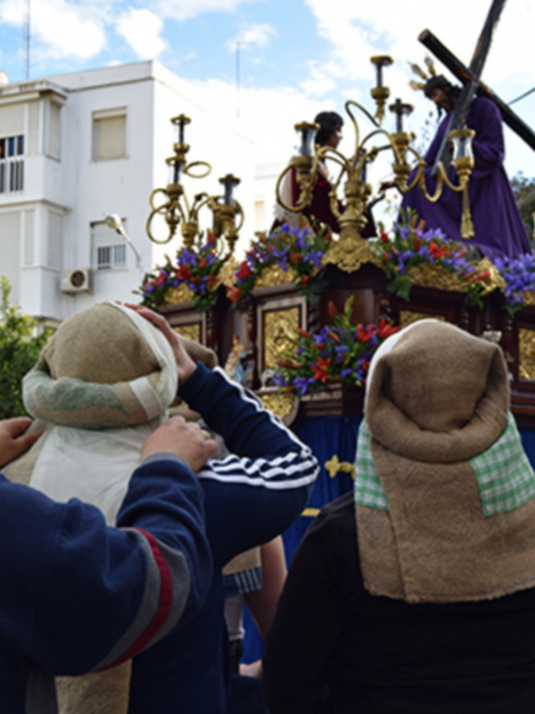 Fotografía de una procesión religiosa con una imagen en procesión y personas participando en ella.