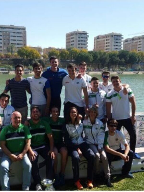 Equipo de piragüismo celebrando en el podio tras una competición en un lago urbano.