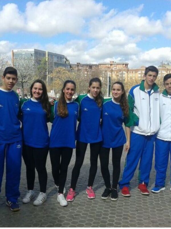 Equipo de jóvenes atletas posando juntos en una plaza urbana.