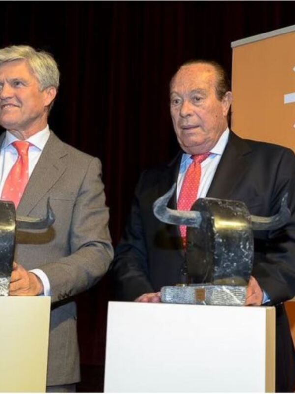 Dos hombres en trajes y corbatas sostienen trofeos en una ceremonia de premiación de FlamencoRadio.com en Andalucía.