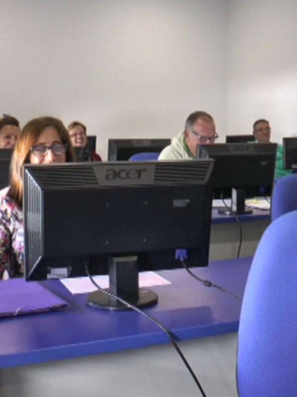 Clase de informática en un aula con estudiantes trabajando en computadoras Acer.