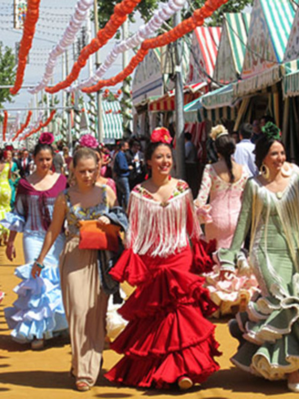 Desfile de mujeres vestidas con trajes típicos de la Feria de Abril en Sevilla, España.