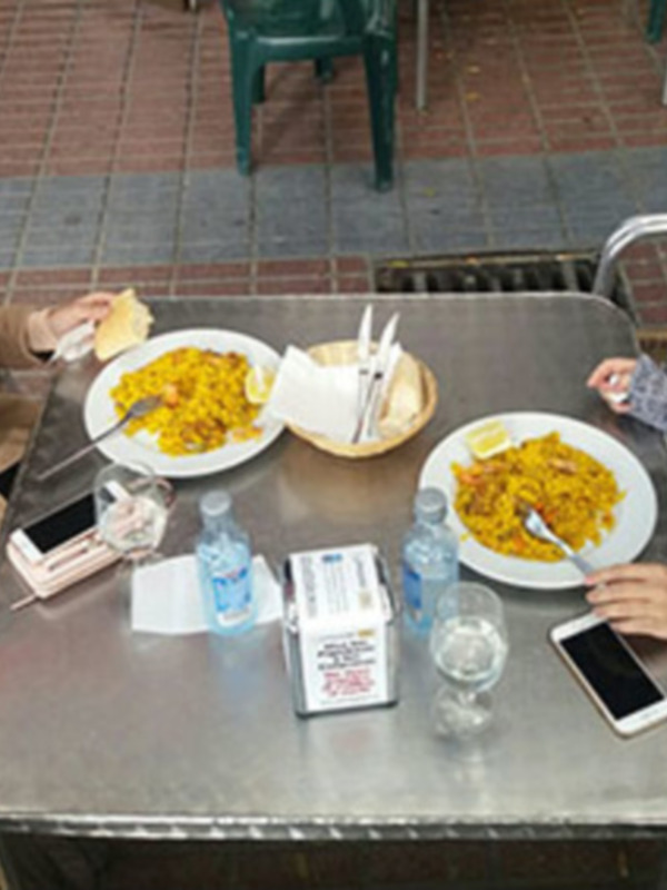 Dos personas disfrutan de un plato de arroz con pollo en un ambiente al aire libre.