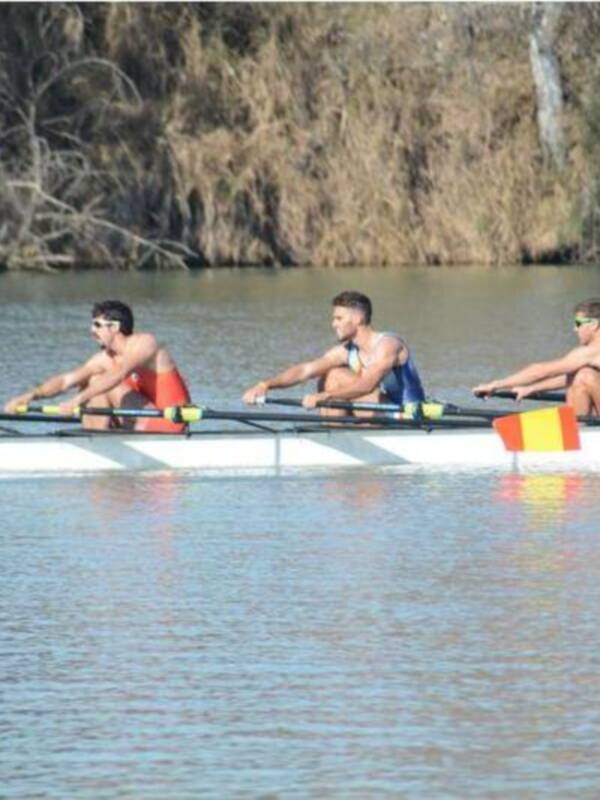 Equipo de remo en competición en un río, con remos y uniformes de España.