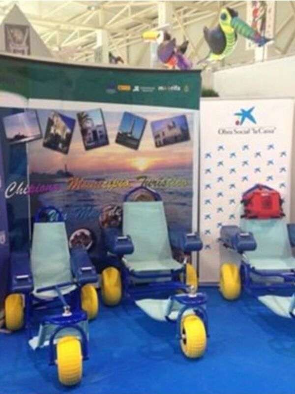 Exposición turística de Chipiona con sillas de ruedas y pancartas promocionales.