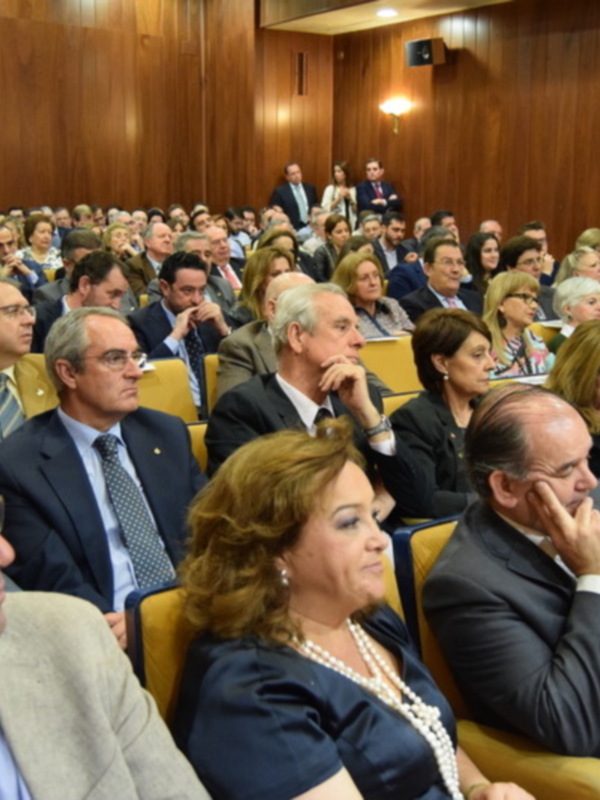 Auditorio lleno de asistentes en un evento formal, vestidos de negocios y trajes formales.