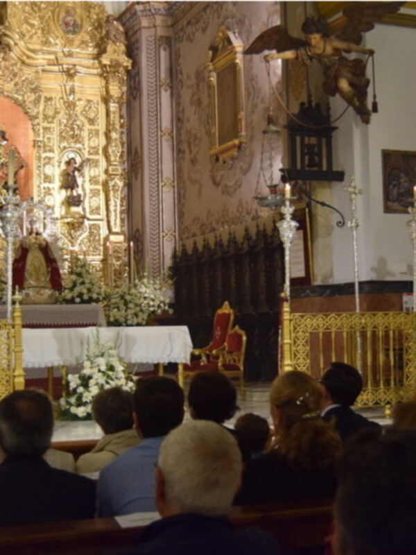 Ceremonia religiosa en una iglesia, con un altar ricamente decorado y una imagen central, mientras una persona habla al público.