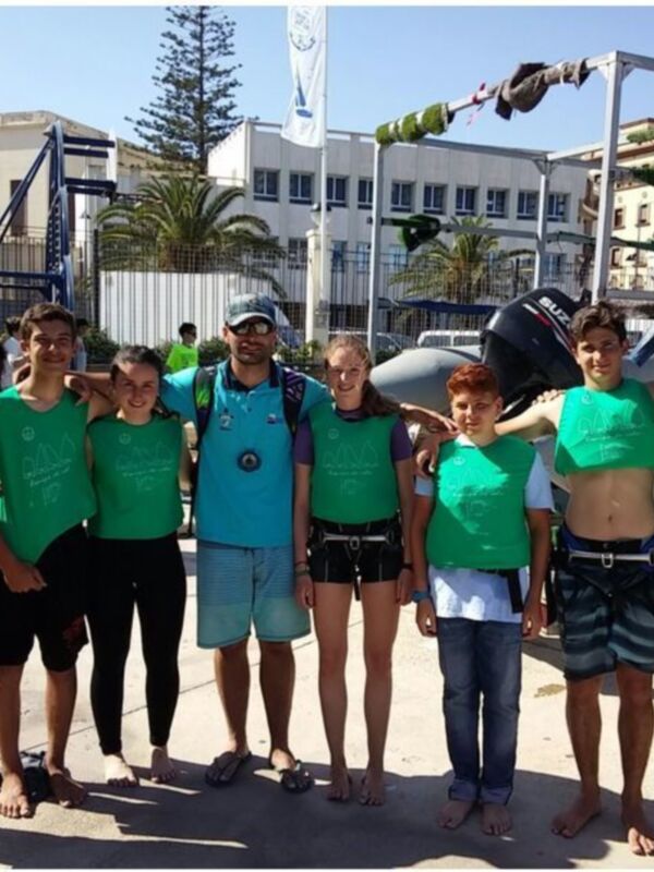 Equipo de jóvenes y adultos posando juntos en una actividad acuática al aire libre.