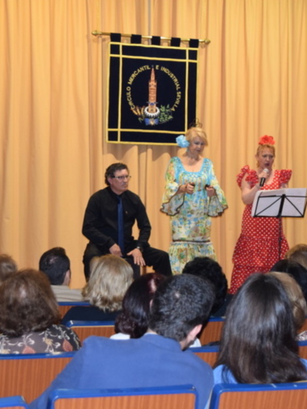 Concierto de flamenco en un auditorio con dos bailarinas y un músico tocando guitarra.