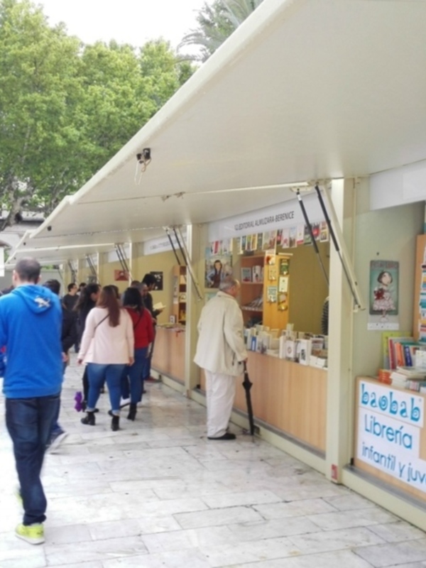 Exposición de libros infantiles y juveniles en un mercado al aire libre.