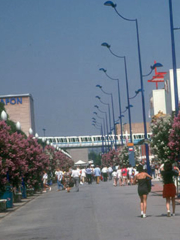 Calle con flores en flor y gente caminando, con edificios y luces de calle en el fondo.