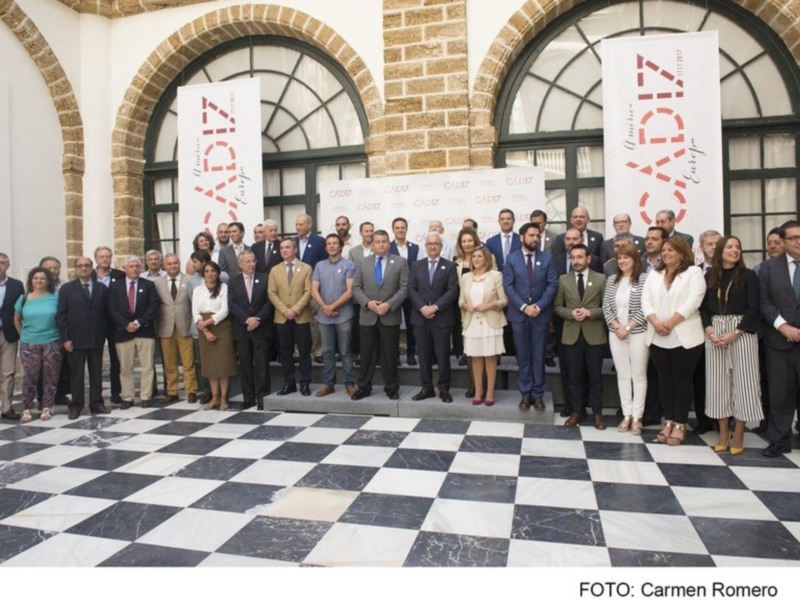 Gruppo di persone in posa per una foto di gruppo in un ambiente elegante con marmo a scacchi e decorazioni architettoniche.