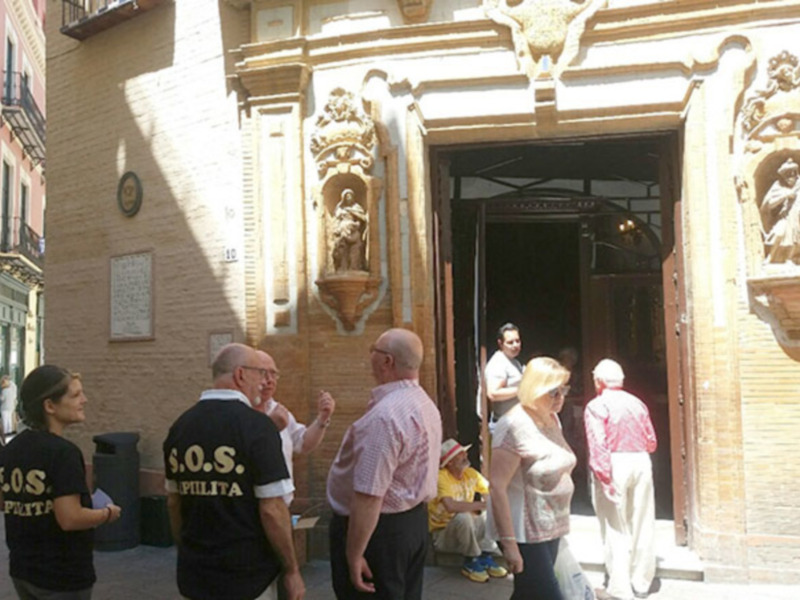 Turistas y guía frente a un edificio histórico con detalles barrocos en una calle de Sevilla.