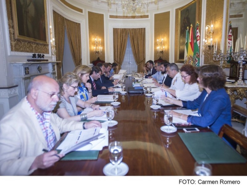 Reunión de trabajo en un salón clásico con participantes discutiendo y tomando notas.