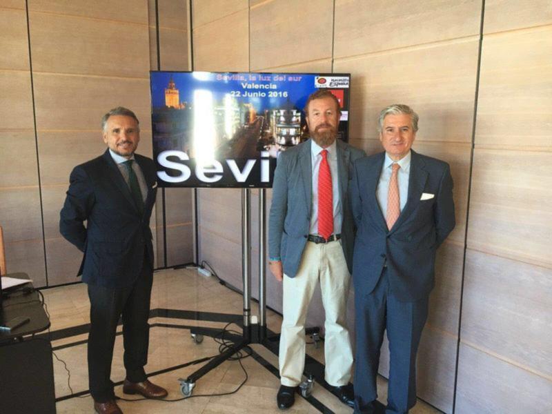 Tres hombres en trajes posan frente a un cartel anunciando Sevilla, la luz del sur, Valencia, 22 de junio de 2016.