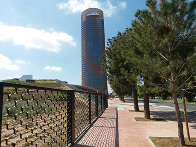 Paseo urbano junto al emblemático edificio de cristal en un día soleado.