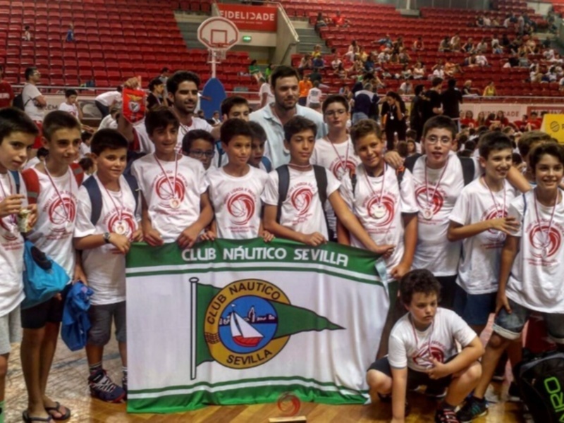 Equipo del Club Náutico Sevilla celebrando en un evento deportivo en una cancha de baloncesto.
