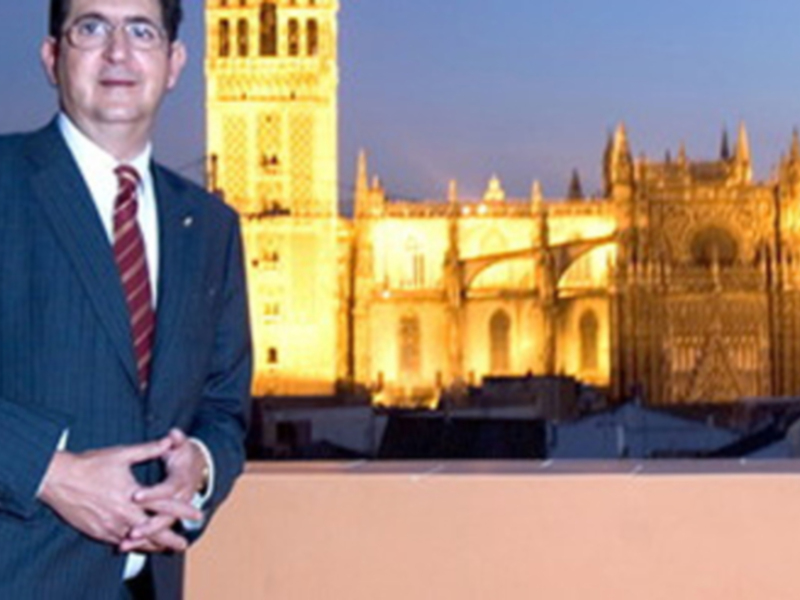 Eduardo Zaplana, Presidente de la Fundación Cajasol, posando frente a la Catedral de Sevilla iluminada en la noche.