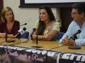 En una conferencia de prensa, tres personas se sientan frente a micrófonos en una mesa con un cartel que dice "Sevilla Siente a Rocío". La imagen muestra a dos mujeres y un hombre, todos con expresiones serias.