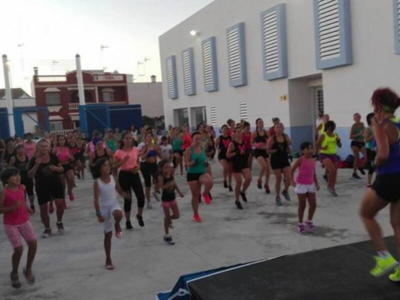 Grupo de personas participando en una clase de zumba al aire libre en una plaza urbana.