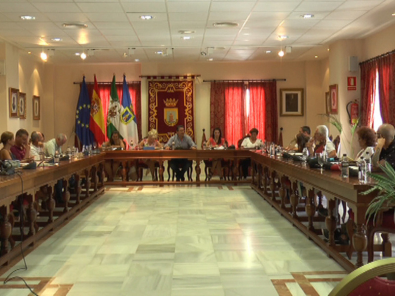 Sala de reuniones con mesa larga, sillas rojas, banderas y un mapa en el fondo.