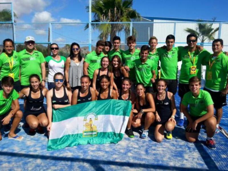 Equipo de padel con bandera y uniformes verdes en una cancha de padel al aire libre.