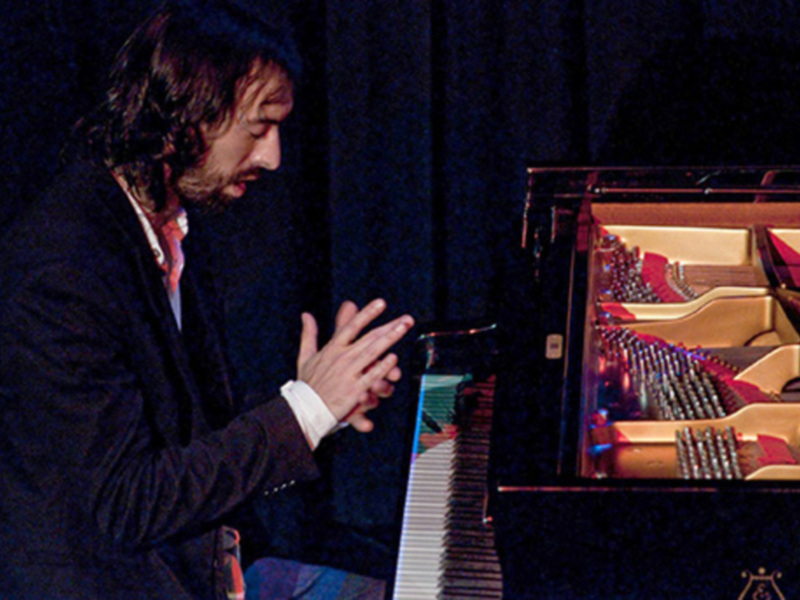 Músico en concierto, concentrado frente a un piano.