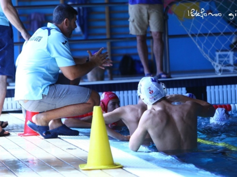 Entrenamiento de waterpolo: un entrenador da instrucciones a jugadores en la piscina.