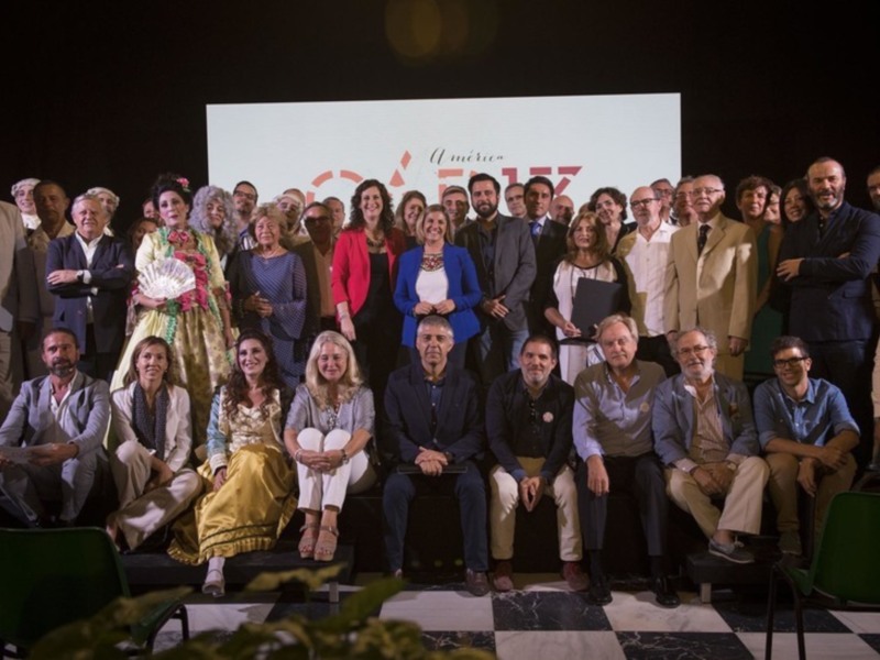 Celebración de un evento con una multitud de personas posando juntos en un escenario iluminado.
