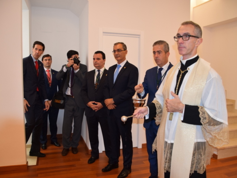 Un grupo de hombres en trajes y un sacerdote en un evento formal, posiblemente una inauguración o ceremonia oficial.