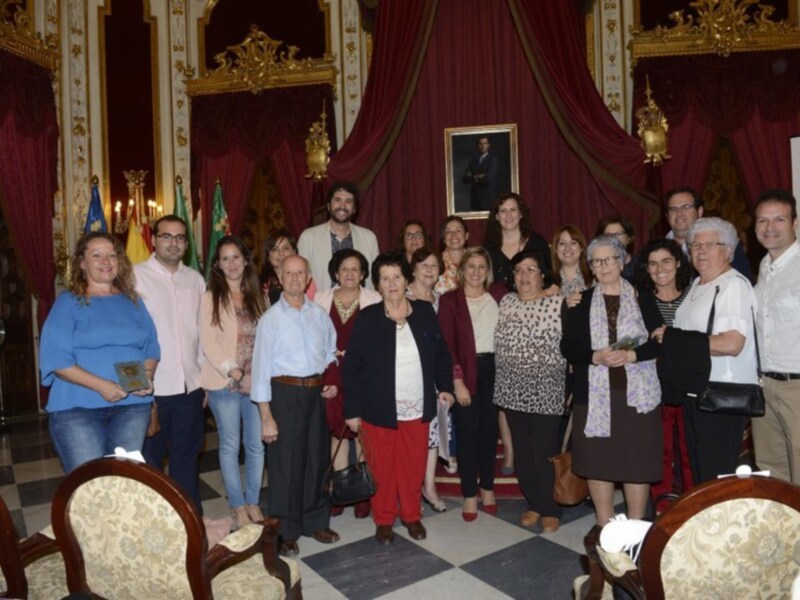 Grupal de personas en un salón decorado con dorado y cortinas rojas, posando para una foto.