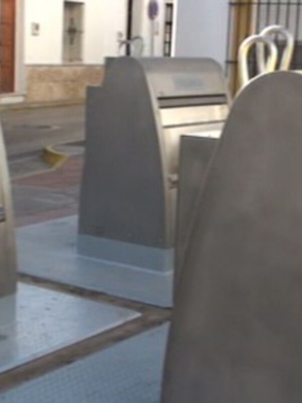 Un área de estacionamiento con un par de coches aparcados y una cerca metálica en el fondo.