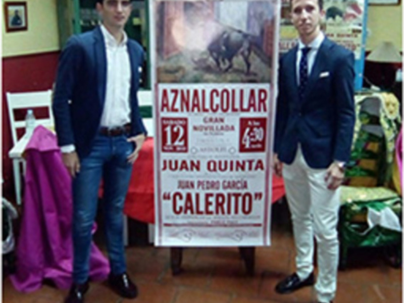 Dos hombres posan con un cartel anunciando la corrida de toros 'Aznalcollar', con Juan Quinta y Juan Pedro García como斗牛士。