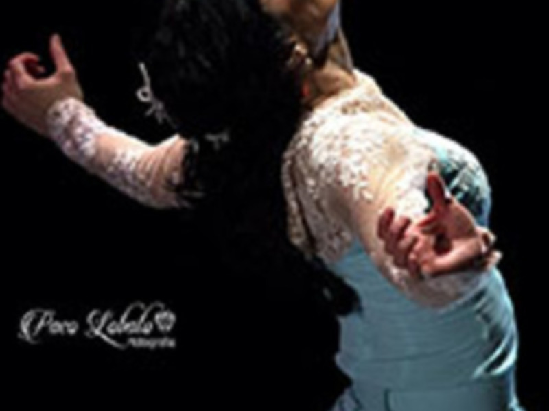 Danza flamenca con vestido blanco y azul, expresión intensa y pose dramática.